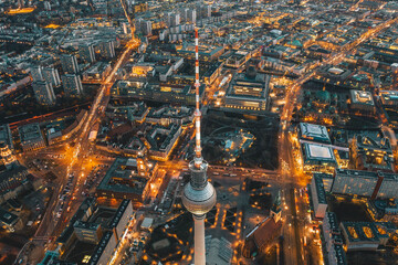 Weite Aussicht auf das schöne Berlin, Deutschland, Stadtbild nach Sonnenuntergang mit beleuchteten Straßen und Alexanderplatz-Fernsehturm, Drohnenansicht