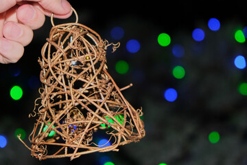 front photo of a handmade bell made of wicker, held by a hand of a you