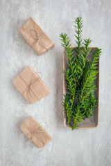 Eco-friendly Wrapped gifts with brown paper and string and bowl with common yew branches next to. Flat lay composition.