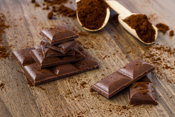 Sliced chocolate pieces with cocoa powder on the wooden surface