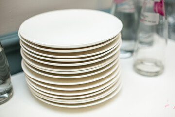 A stack of plates on the table among other items