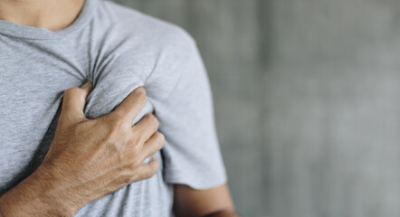 Man having Chest pain against grey wall background with copy space