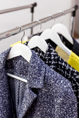Jackets hanging on wooden clothes hangers in a modern clothing store, shop, mall, market, showroom. Fashion collection. Personal stylist, sales, shopping. Dressing room. Retail