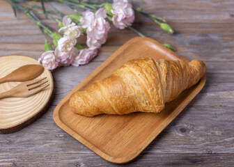 Fototapeta na wymiar tasty croissants in a wood plate on dark wooden table, closeup. French pastry