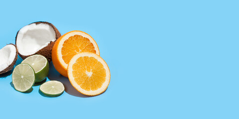 Fresh juicy orange, coconut and green lime isolated on blue background. Concept of Healthy eating and dieting. Travel and holiday concept