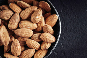 Fresh nuts almonds in steel bowl on dark background. Top view.