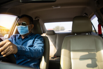 Daylight a man driving hands to hold the steering wheel to control the car carefully While traffic congestion. Blur a male wearing a face mask. Closeup and select the focus on hand. Blurred background