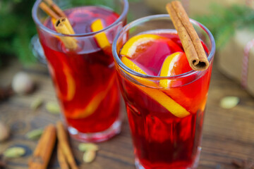 Close-up of two glasses of hot wine, mulled wine, decorated with a cinnamon stick, a Christmas tree in the background. Winter drink.