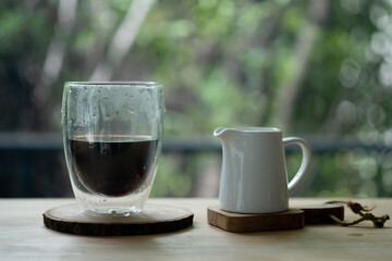 Morning black coffee in glass with fresh milk in ceramic jar