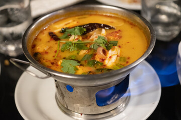 Tom Yum kung with herb on hot pot. Spicy Thai traditional food