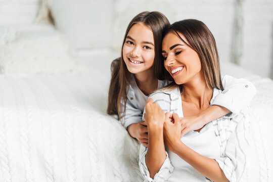 Beautiful child hugs her mother on a white background, smiling looking at the camera. Place for text