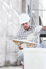 plasterer man at work, take the mortar from the bucket to plastering the wall of interior...