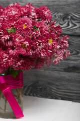 A bouquet of red chrysanthemums on a background of black pine boards.