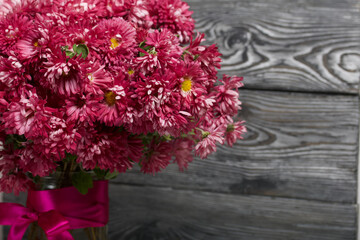 A bouquet of red chrysanthemums on a background of black pine boards.