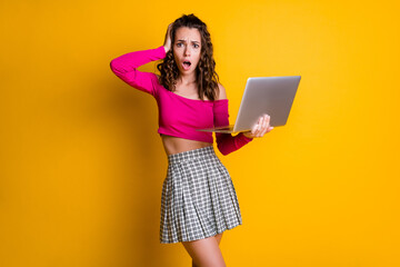 Naklejka premium Photo of lady curly hairdo arm hold netbook hand head open mouth terrified look horror mistake wear pink top unclothed shoulders skirt isolated yellow color background