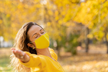 Happy woman wearing protective mask in autumn park