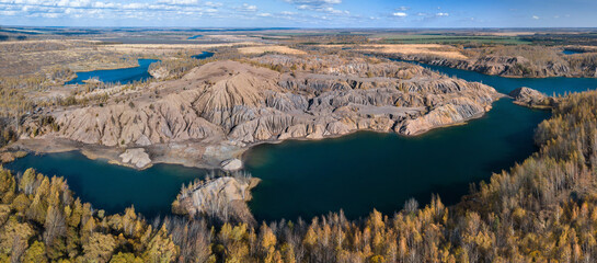 Fancy and unusual autumn aerial landscape of Romantsev mountains wih blue lakes, yellow trees and mud erosion looks like alien surface of Mars. Russia. Tula national park