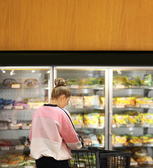 Woman choosing frozen food from a supermarket freezer