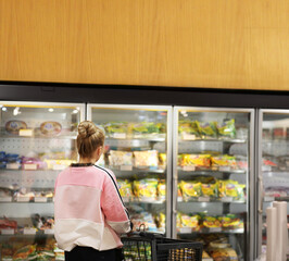 Woman choosing frozen food from a supermarket freezer