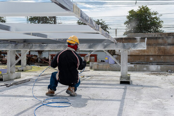 The painter is working to fireproof paint on steel structure with spray gun, at industrial factory.