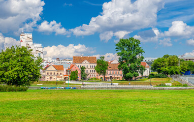 Traeckaje Suburb with old buildings in Trinity Hill district and grass lawn with green trees in Minsk city Nemiga historical centre, blue sky white clouds in sunny summer day, Republic of Belarus