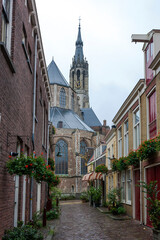 Fototapeta na wymiar Trompetstraat, Delft, South Holland, Netherlands, with a glimpse of the New Church (Nieuwe Kerk) at the end of the street