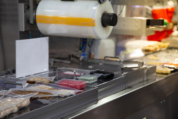 Linear tray food heat sealing and packaging machine.