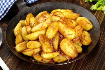 Classic Roasted Potatoes in a Pan with Bacon and Onions on wooden Background