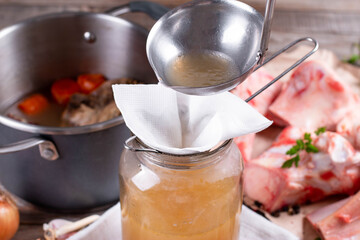 Passing the bone broth through a sieve and through a paper napkin. Concentrated Bone Broth in a Jar