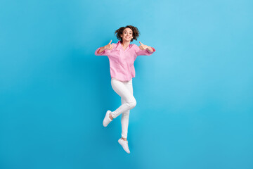 Fototapeta na wymiar Full body photo of positive girl jump show thumb up sign wear pink formal clothes gumshoes isolated on blue color background