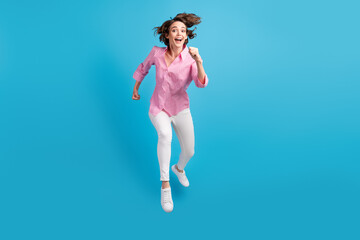 Full size photo of cheerful girl jump run in camera wear formal clothes gumshoes isolated over blue pastel color background