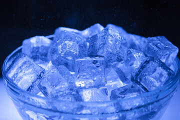 Bowl of wet ice close-up with water drops falling over