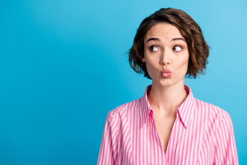 Photo of curly lovely woman wear pink striped shirt look empty space lips pouted isolated blue...