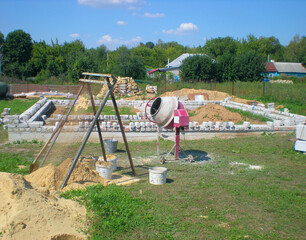 concrete mixer and mesh for sifting sand on the background of a house under construction