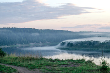 Fototapeta na wymiar Thick fog on the autumn Bank of a wide river on a clear Sunny morning