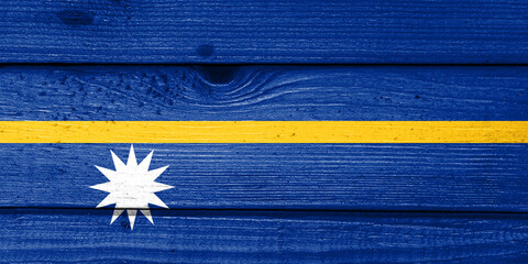 Nauru flag painted on old wood plank background. Brushed natural light knotted wooden board...