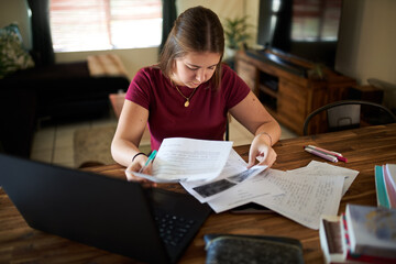 Teenager girl doing homework at home. Online education and elearning concept during quarantine
