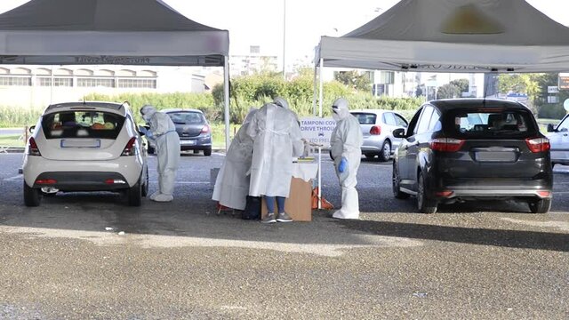 Double workstation for test drive through swabs for the diagnosis of the covid-19 coronavirus, with two cars and doctors completely covered by masks and covering suits