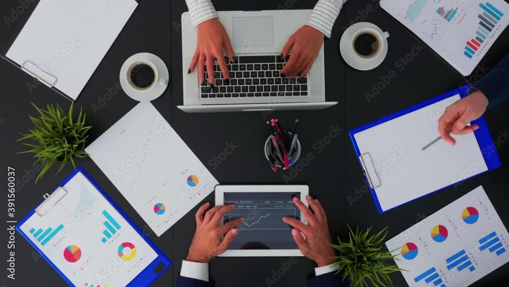 Poster directly above view of business people working with financial documents and presentation on tablet a