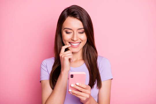 Photo of cute young lady hold cellphone touch cheek dressed casual wear isolated on pink color background
