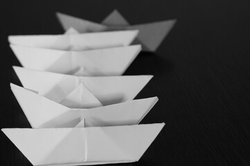Several paper boats on the table. One of them is orange.