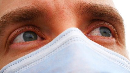 Close-up of irritated eyes of a sick man with a protective face mask