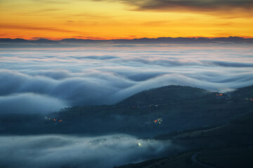 Blue waves of fog before sunrise between mountains and valleys