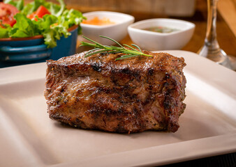 Grilled chorizo ​​steak with rind fries, chili sauce and chimichurri sauce, lettuce and tomato salad and a crystal glass of Jamaican water.