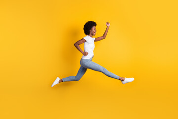 Fototapeta na wymiar Full length body size photo of young female millennial with black skin jumping high running fast cheering isolated on bright yellow color background