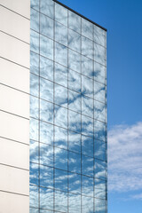 The steel and glass facade of a building reflects the sky