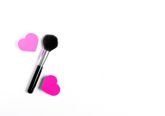 Obraz na płótnie Canvas Make up brush and two heart shaped sponges are making the percent symbol against the white background. Concept of discounts in cosmetic shop or beauty salon. Copy space