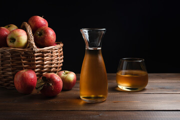 Glass of apple juice with red apples on a wooden table, close up. Dark background. Copy place. Horizontal