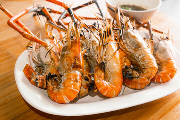 Closeup Grilled Tiger Shrimps with seafood sauce on wood table