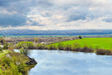 Fototapeta na wymiar Spring landscape with river, green field and picturesque cloudy sky